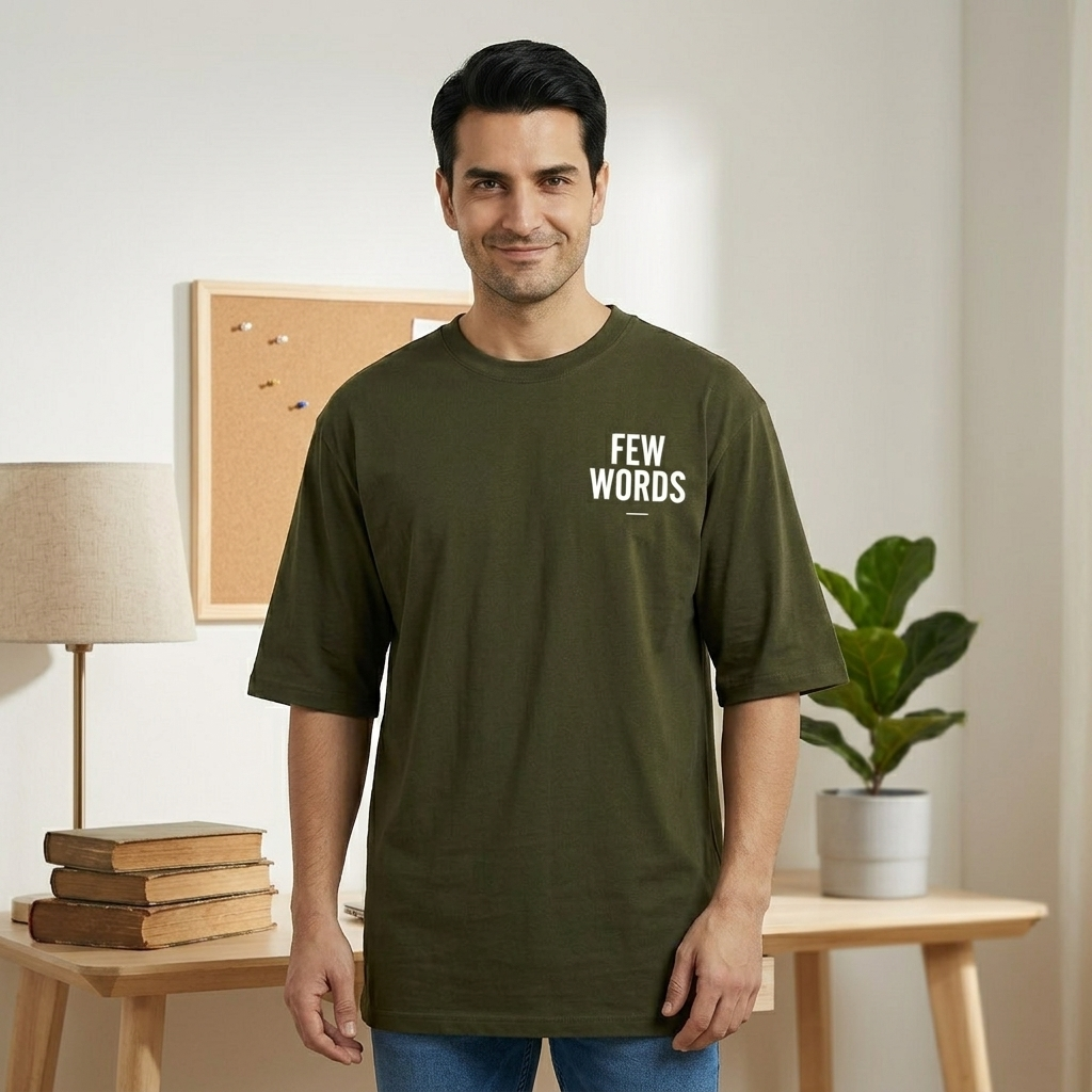 Man wearing a green t-shirt with 'FEW WORDS' text in a room with books and a plant.