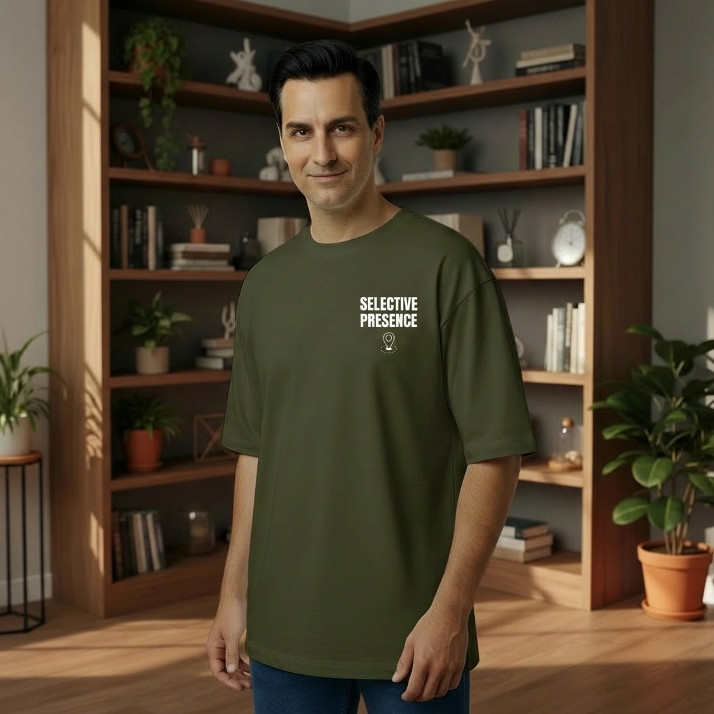 Man wearing a green t-shirt with 'SELECTIVE PRESENCE' text in a room with bookshelves and plants.