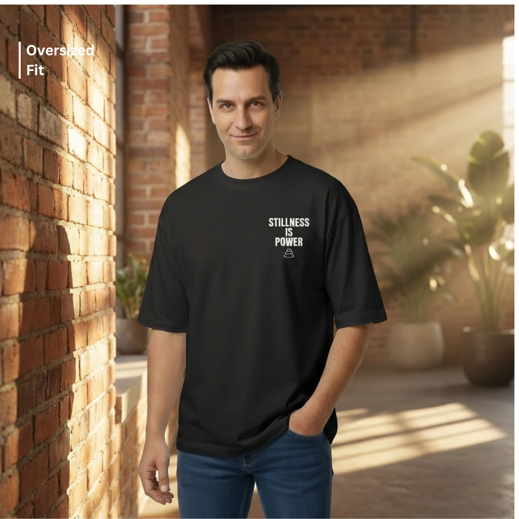 Man wearing a black t-shirt with text standing against a brick wall.