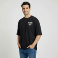 Man wearing a black t-shirt with ' ACTIONS ONLY' text on a plain background