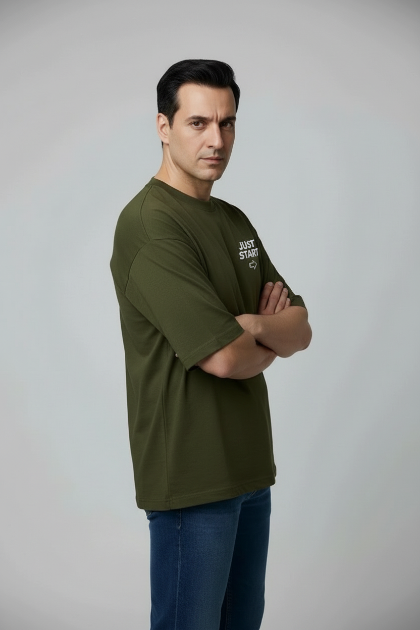 Man wearing a green t-shirt with text and blue jeans against a gray background